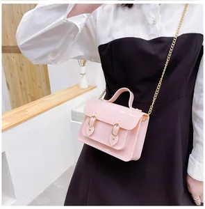 Side view of a pink jelly Cambridge satchel bag with gold chain strap worn by a model