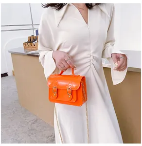Detail of bright orange jelly Cambridge crossbody bag with chain strap and handle