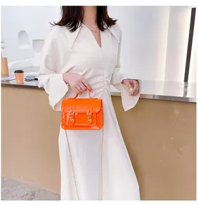 Detail view of bright orange jelly Cambridge satchel bag with gold chain strap