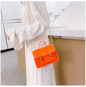 Stylish bright orange jelly Cambridge bag with gold chain strap shown on model profile