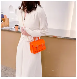 Model wearing a bright orange jelly Cambridge satchel bag with a gold chain strap