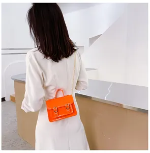 Back view of a model wearing a bright orange jelly Cambridge bag with a gold chain strap