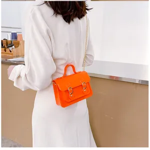 Vibrant orange jelly satchel bag shown on a model in a casual indoor setting.