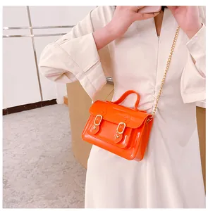 Close-up of orange jelly Cambridge bag with gold chain strap on model