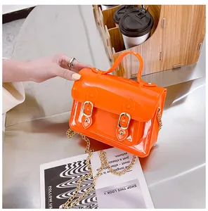 Close-up view of a vibrant orange jelly Cambridge bag with top handle and gold chain strap.