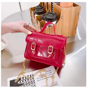 Detailed view of a bright red jelly Cambridge bag featuring a golden chain strap