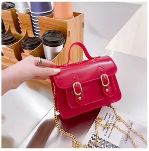 Detailed close-up of a stylish pink jelly Cambridge bag with gold chain strap in a cafe