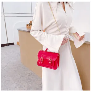 Red glossy jelly Cambridge crossbody bag style shown on a model wearing a white dress