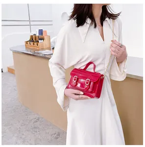 Vibrant red glossy jelly Cambridge bag with gold chain strap worn as a stylish crossbody