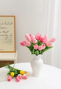 Close-up of pink and yellow PU artificial tulip flowers in a white ceramic vase