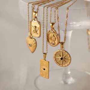 Collection of five vintage style gold stainless steel coin pendant necklaces on a glass rim