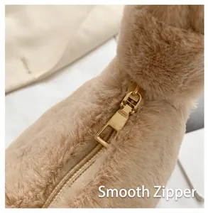 Detailed view of the smooth golden zipper on a beige plush faux fur shoulder bag.