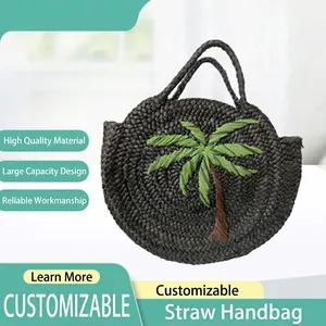 Front view of a dark woven straw handbag featuring a green palm tree embroidery.