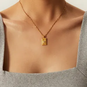 Gold stainless steel coin pendant necklace with textured pattern and tiny stone on model