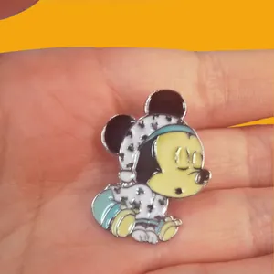 Macro detail of a Mickey Mouse baby sleeping enamel pin badge being held in a hand