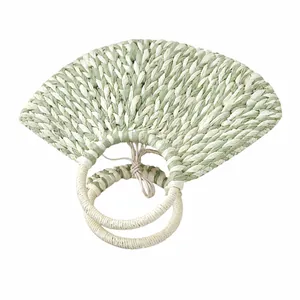 Close-up of a handmade woven half-moon handbag showing detailed green and white textures