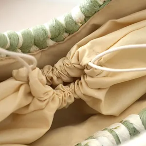 Detail of hand-woven semicircle bag with beige drawstring lining and green weave.