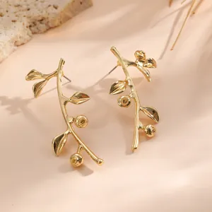 Detailansicht goldener Blattzweig-Ohrringe mit Beerenmotiven in eleganter Beleuchtung