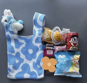 Close-up of blue floral knitted gift bag with plush rabbit charm and snack contents