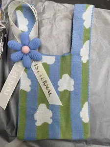 Close-up of knitted gift bag featuring a blue flower and 'Love is Eternal' ribbon