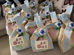 Close-up view of multiple knitted gift bags featuring floral charms and greeting cards.