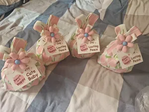 Close-up of four pink knitted bunny-ear gift bags with decorative flowers and tags