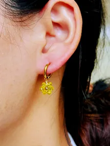 Détail d'une boucle d'oreille fleur en perles jaunes faite main avec placage à l'or