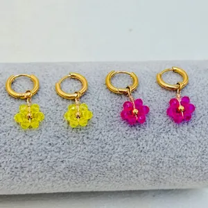Vue détaillée de breloques fleurs en perles jaunes et roses sur anneaux dorés inox