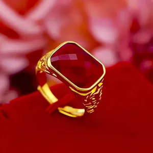 Macro view of men's gold ring with a large rectangular red stone and engraved band.