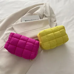 Vibrant quilted cloud makeup bags in magenta and yellow displayed on a stylish beige blazer.