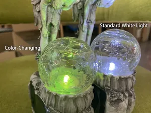 Macro detail of two glowing solar crackle glass balls held by fairy garden statues