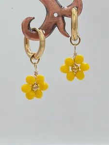 Gros plan détaillé de boucles d'oreilles fleurs en cristal jaune avec créoles en acier doré