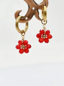Gros plan de breloques fleurs en cristal rouge fait main sur boucles d'oreilles.