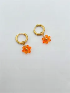 Détail de breloque fleur en cristal orange sur créoles en acier inoxydable doré