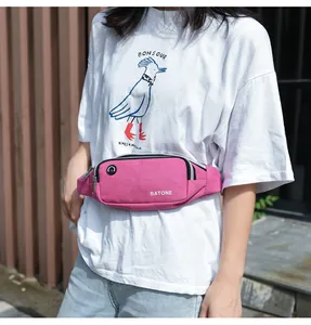 Detailed view of a pink sports waist bag with headphone port worn by model outdoors