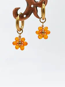 Détail de créoles en acier inoxydable avec breloques de fleurs en cristal orange