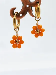 Vue détaillée de boucles d'oreilles fleurs orange faites main avec anneaux dorés