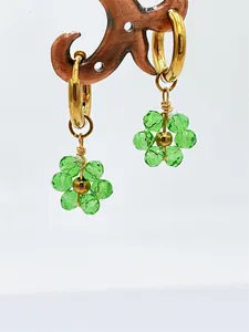 Gros plan de boucles d'oreilles fleurs en cristal vert faites main avec créoles dorées.