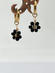 Détail rapproché de breloques fleurs noires faites main sur créoles en acier doré