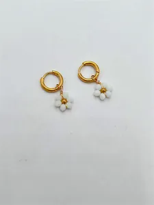 Détail de boucles d'oreilles fleur en perles blanches avec anneaux en acier doré.