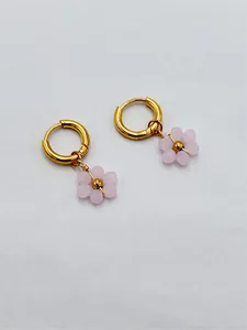 Vue détaillée de breloques fleurs en perles roses sur créoles en acier inoxydable doré.