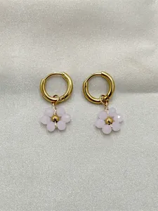 Détail de boucles d'oreilles créoles dorées avec charms fleurs en perles roses.