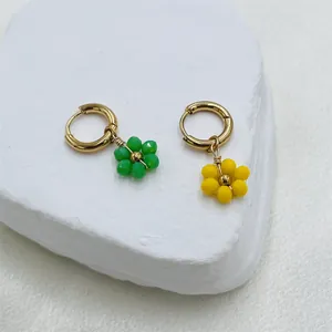 Détail des pendentifs fleurs en perles sur des créoles dorées en acier inoxydable.