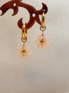 Gros plan de boucles d'oreilles fleurs en perles roses avec créoles en acier inoxydable doré.