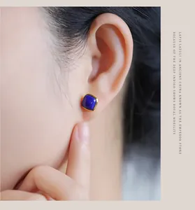 Close-up of square lapis lazuli stud earring in gold plated silver on ear