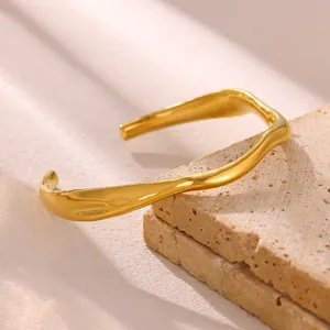 Detailed view of the irregular wave texture on an 18k gold plated open cuff bracelet.