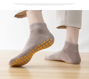 Detailed view of non-slip yoga socks with orange silicone grip pads on wooden floor