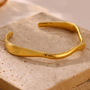 Detailed view of the elegant wavy texture on a gold-plated titanium steel cuff bangle