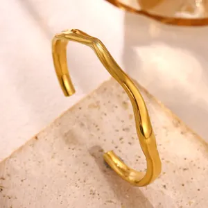 Close-up of minimalist irregular wavy 18k gold plated titanium steel open bangle