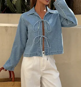 Close-up of French style tie-front denim jacket details for women in light blue wash.